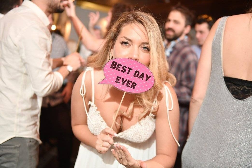 כלה מחזיקה שלט „Best day ever” על הרחבה